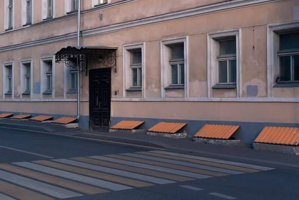 односкатные козырьки над входом в дом и на фасаде над окнами подвального помещения