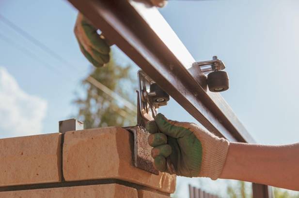 установка верхней пластины с роликами для фиксации откатных ворот в вертикальном положении