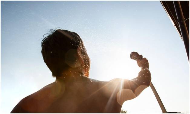 Мужчина вынужден держать душевую насадку самостоятельно ведь не построил летний душ