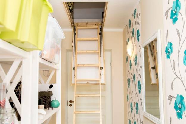 узкая чердачная лестница из дерева в комнате небольших размеров